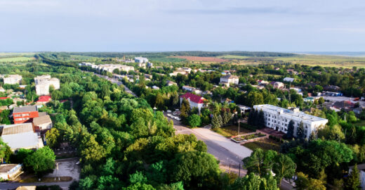 Donduseni with multiple residential buildings and greenery, fields on the background, view from the drone in Moldova