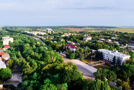Donduseni with multiple residential buildings and greenery, fields on the background, view from the drone in Moldova
